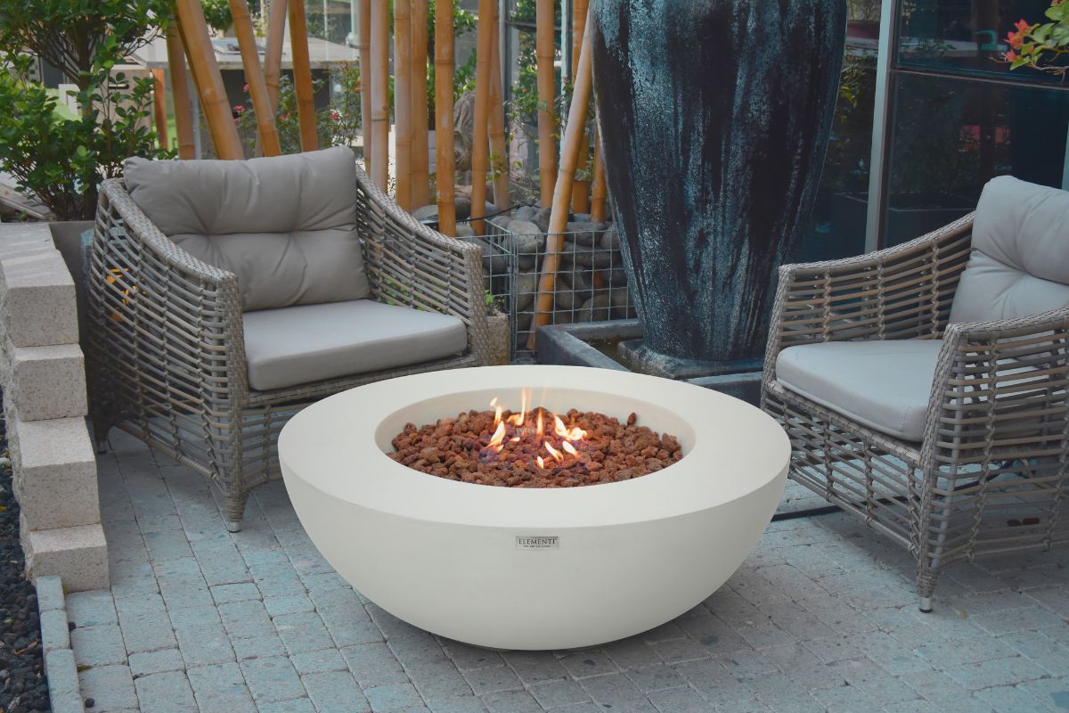 Feuerstelle LUNAR BOWL Cream White im Garten mit Geflechtsesseln