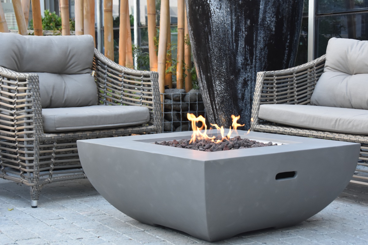 Tisch WESTPORT mit brennendem Feuer auf der Terrasse bei Rattansesseln