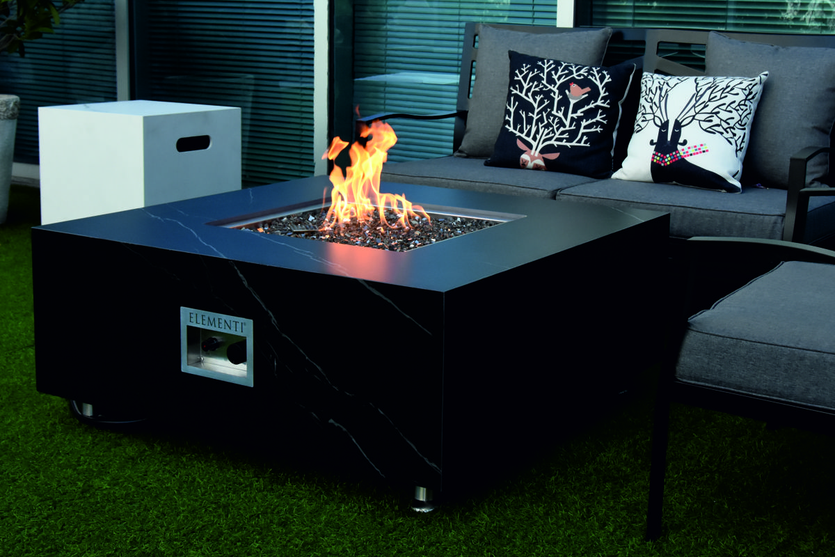 Tisch SOFIA mit brennendem Feuer auf der Terrasse vor einem Sofa